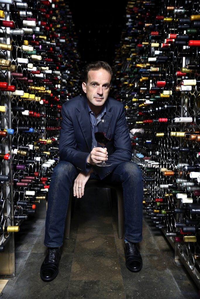 David Forer MW seated in a wine cellar holding a glass of red wine