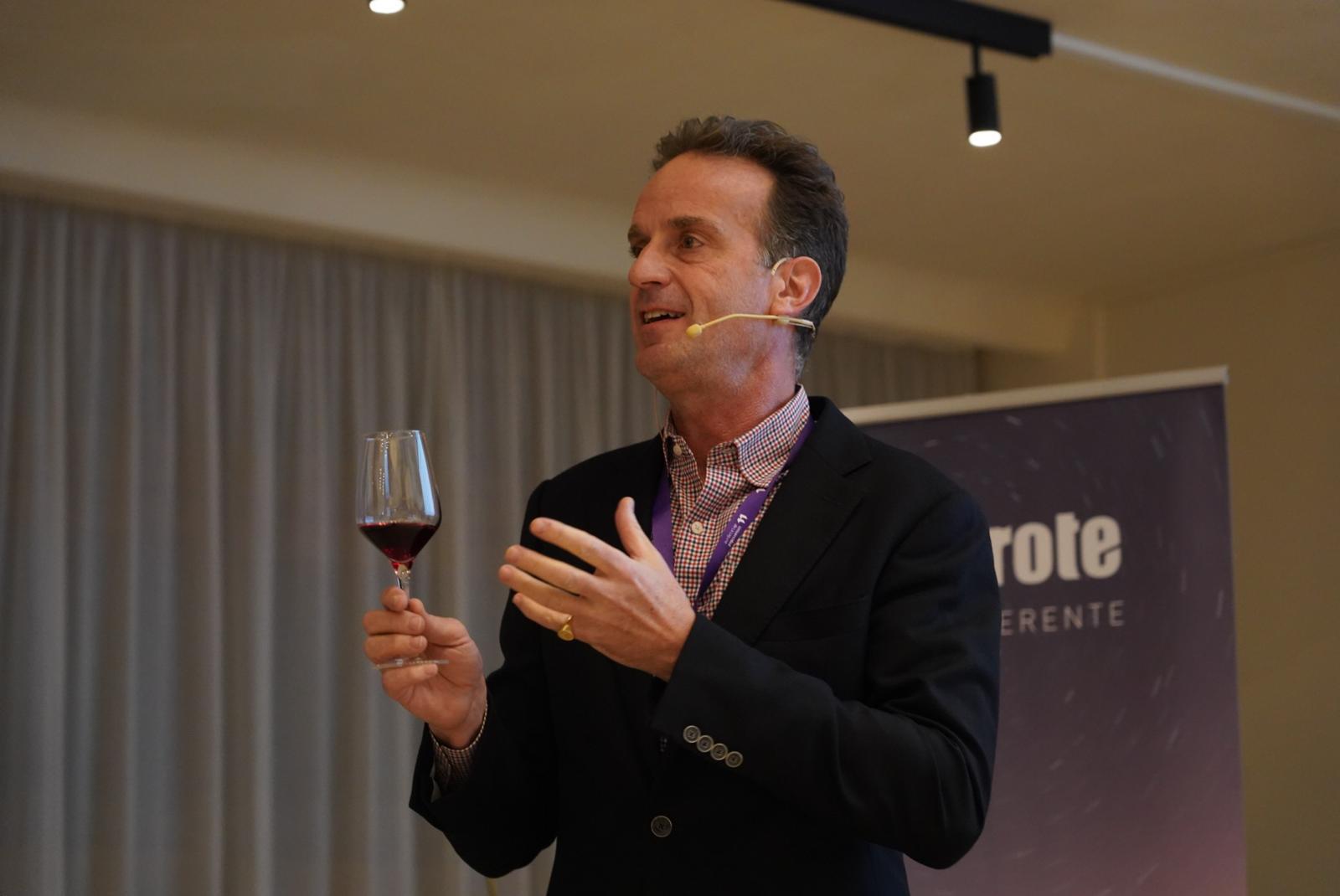 David Forer speaking at a wine event with a glass of red wine